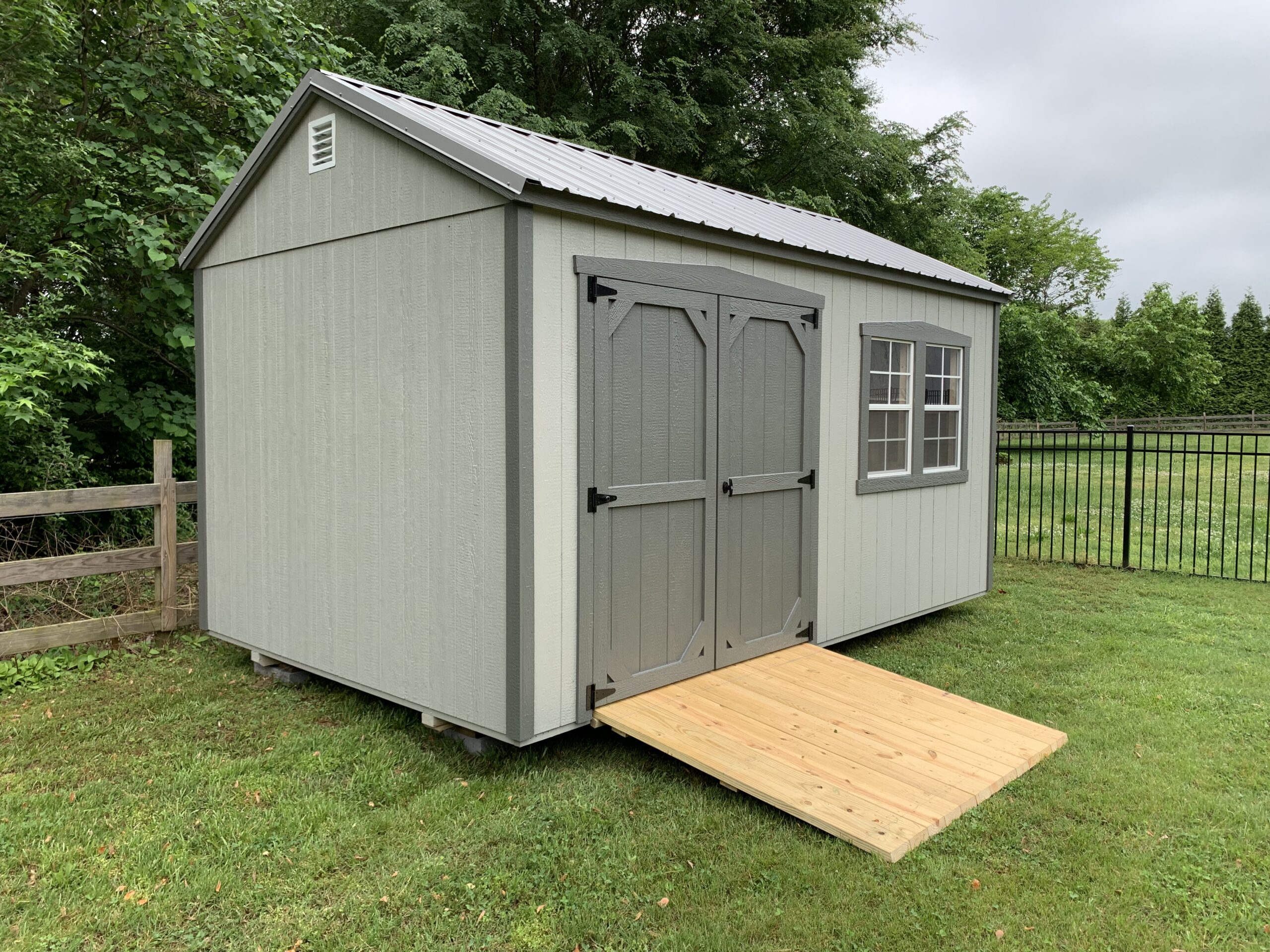 Gray storage shed with fence and ramp